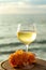 Aperitif cold white wine served in glasses with pink grapes on outdoor tessace witn sea view