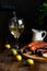 Aperitif concept. Wine pours into a glass goblet. On the table, meat appetizer, fried sausages, salami, cheese, olives.