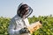 apiarist in beekeeping suit holding honeycomb