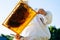 Apiarist wearing white protective clothing and gloves holding honeycomb full of bees