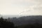 Apocalyptic romantic landscape with barren trees and smoking industrial pipe