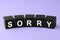 Apology. Word Sorry made of black cubes on violet background