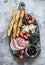 Appetizer board. Gorgonzola, ham, salami, olives, fruit, grassini on a rustic chopping board on a gray background, top view