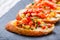 Appetizer bruschetta with chopped vegetables on ciabatta bread on stone slate background close up.