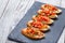 Appetizer bruschetta with chopped vegetables on ciabatta bread on stone slate background close up.