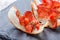 Appetizer bruschetta with jerky prosciutto on thinly sliced ciabatta bread on stone slate background close up.