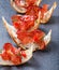 Appetizer bruschetta with jerky prosciutto on thinly sliced ciabatta bread on stone slate background close up.