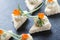 Appetizer canape with red caviar and cream cheese on stone slate background close up.