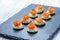 Appetizer canape with salmon, cucumber and cream cheese on stone slate background close up.