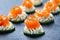 Appetizer canape with salmon, cucumber and cream cheese on stone slate background close up.
