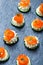 Appetizer canape with salmon, cucumber and cream cheese on stone slate background close up.