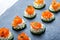 Appetizer canape with salmon, cucumber and cream cheese on stone slate background close up