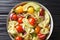 Appetizer Farfalle pasta salad with ripe avocado, onion and tomato closeup in a bowl. horizontal top view