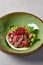 Appetizer - roast beef with sauce, cucumber and onion in ceramic bowl. Roast beef in modern ceramic dishware. Handmade dinner