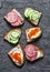 Appetizer sandwiches with red caviar, egg, sausage, cucumber and cream cheese on grey background