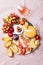 Appetizers, antipasti snacks and rose wine in glasses. Cheese and fruit platter on marble board over pink linen tablecloth