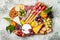 Appetizers table with antipasti snacks. Cheese and meat variety board over grey concrete background. Top view, flat lay.
