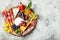 Appetizers table with antipasti snacks. Cheese and meat variety board over grey concrete background. Top view, flat lay.