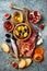 Appetizers table with italian antipasti snacks and wine in glasses. Charcuterie board over grey concrete background.