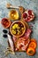 Appetizers table with italian antipasti snacks and wine in glasses. Charcuterie board over grey concrete background. Top view