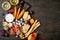 Appetizers table with italian antipasti snacks and wine in glasses. Cheese and charcuterie variety board over rustic wooden table