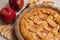 Appetizing Apple pie, ceramic mold, red apples, knife on a light wooden background.