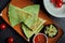 Appetizing baked quesadilla with minced chicken of cheese in green tortilla on a ceramic plate on a black background. Modern