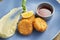 Appetizing breadcrumb shrimp croquettes with red sauce on a blue plate. Wooden background. Close up view. Tasty seafood, Film