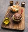 Appetizing burger only meat and eggs and butter, with rice and vegetables, spices on vintage cutting board