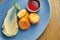 Appetizing chicken croquettes breaded with red sauce and mashed potatoes on a blue plate with spicy red sauce. Wood background
