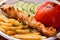 Appetizing chicken kebab, fried potatoes chips, grilled tomato and fresh sliced cucumbers close-up