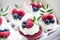 Appetizing cupcakes with white cream, raspberries and blueberries decorated with  leaves.