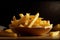 Appetizing french fries in a wooden plate on a dark background