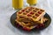 Appetizing fried pumpkin Viennese wafers with cranberry berries on a black plate on cotton sackcloth with yellow glasses of coffee