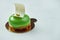 Appetizing green cake with a glossy texture, white chocolate and pistachio flavor on a white texture background. Stylish dessert