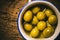 Appetizing green salted olives on old wooden table