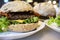 Appetizing hamburger with beef, cheese, lettuce and fried bacon on a plate, among other cheeseburgers