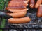 Appetizing Hot dogs, sausages, wieners fry and turn the tongs on the grill barbecue. Family picnic