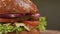 Appetizing juicy burger with onion, cheese, tomato, beef cutlet on a salad leaf close-up on a gray background.