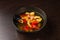 Appetizing looking seafood soup with mussels shrimp red peppers in a plate on a wooden table