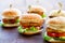 Appetizing mini chicken burgers on wooden surface.