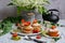Appetizing muffins with strawberries and kiwi, a bouquet of lilies of the valley, a teapot and a green napkin on a light