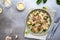 Appetizing pasta with mushrooms, spinach and cheese on a gray concrete background.