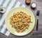 Appetizing pasta with smoked salmon, herbs and onions on a yellow plate on a striped napkin salt and pepper on wooden rustic