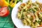 Appetizing pasta with vegetables and cheese on a white plate close-up