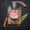 Appetizing piece of raw pork steak on vintage cutting board with herbs and spices for meat with a knife on wooden rustic backgroun