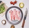 Appetizing pieces of raw bacon in a frying pan with oil, stabbed, herbs, salt and spices wooden rustic background top view clos