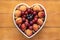 Appetizing plate of seasonal ripe fresh fruit in a white heart-shaped plate - healthy eating with apricots, grapes, strawberries,