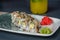 Appetizing portion of sushi rolls philadelphia with eel, soft cheese, on gray plate, background of yellow fruit juice