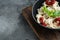 Appetizing ravioli with tomato sauce  cheese and basil with basil parmesan and tomatoe in black bowl   on gray background   with